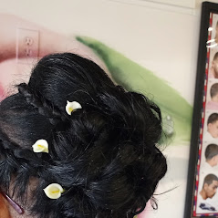 A close-up of a woman hairstyle with small white flowers, near photo frame.