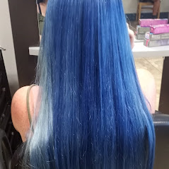 A woman showcasing her long, straight blue color hair in a salon