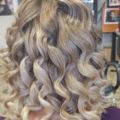 A close-up of wavy, blonde hair, styled beautifully with a salon background.