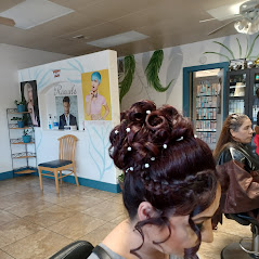 A woman with styled hair sits in a salon, posters and products on shelves in the background.
