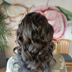A woman showcasing her long, curly, and well-styled hair in a room.