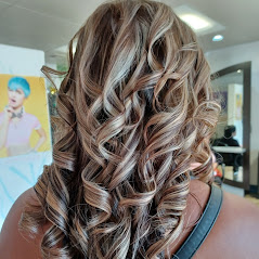 A woman showcasing her long, curly, and well-styled hair in a salon