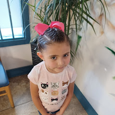 Child wearing ribbon headband with plant in background